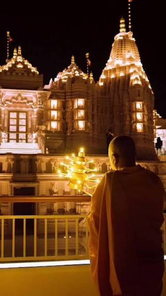 Vedic Priest holding multi-tiered brass deepam during Ganga Aarti ceremony in Abu Dhabi UAE